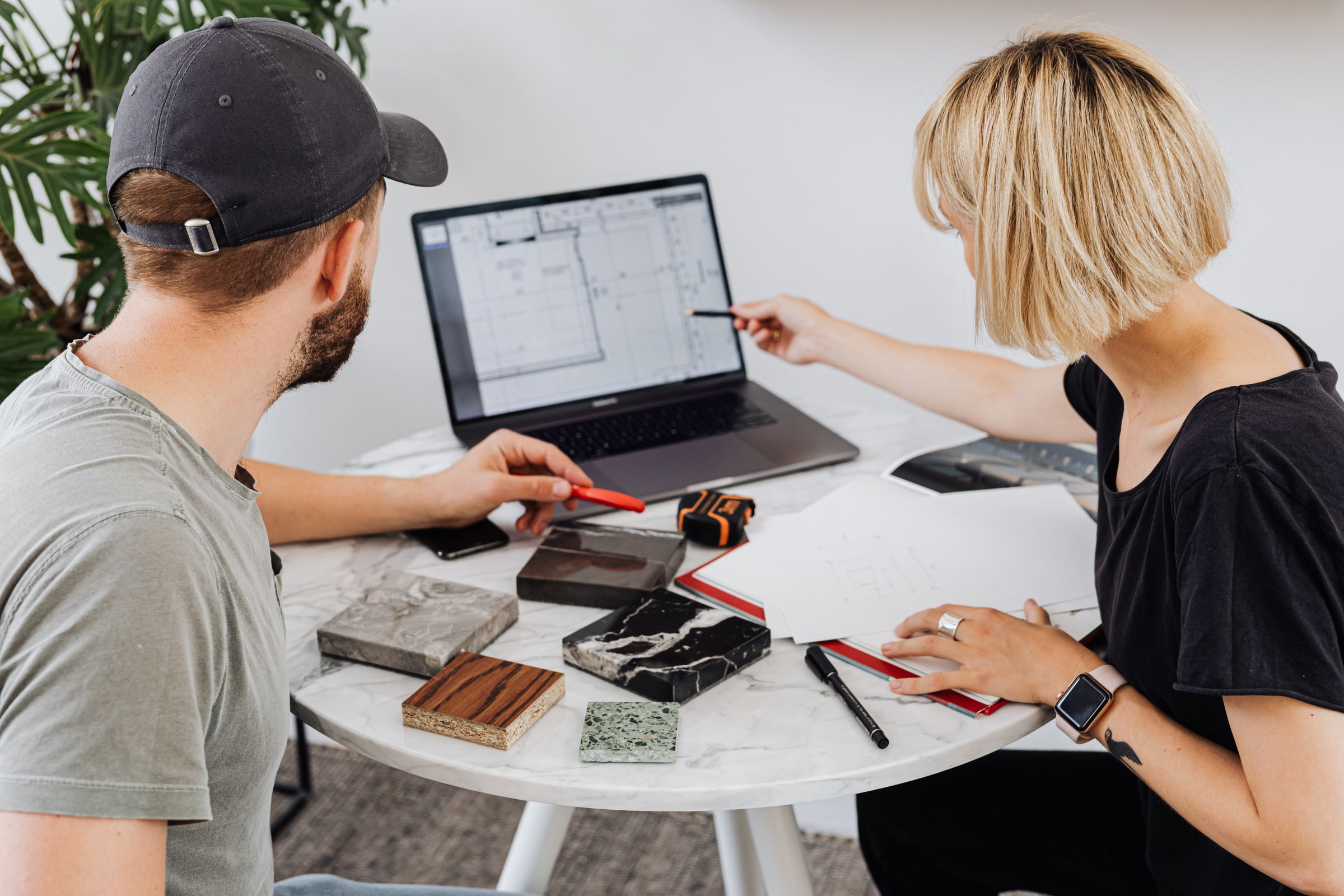 Designer and client reviewing work on a laptop at a table