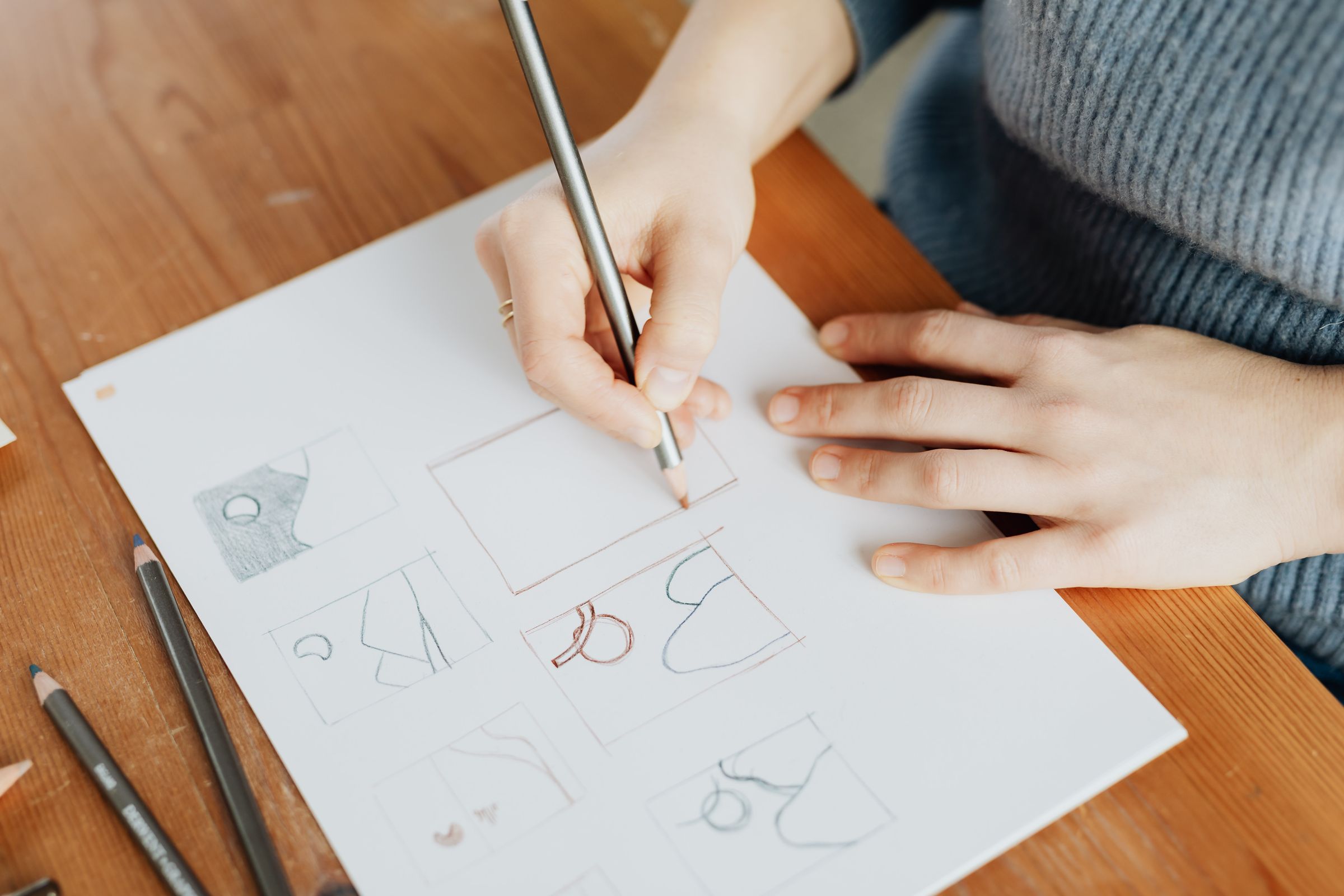Designer sketching logo concepts in pencil on paper